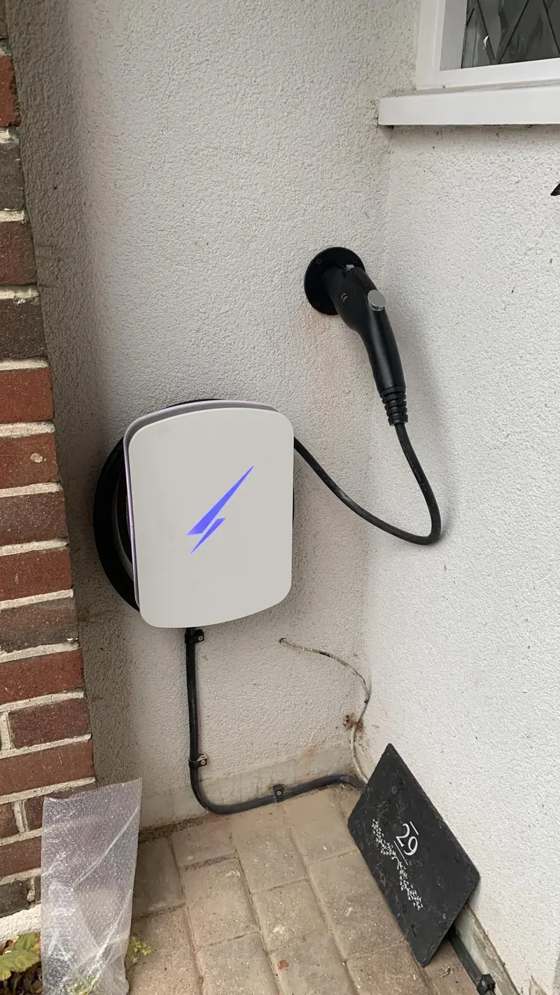 White EV charger with a purple light on a rendered wall in a side passage