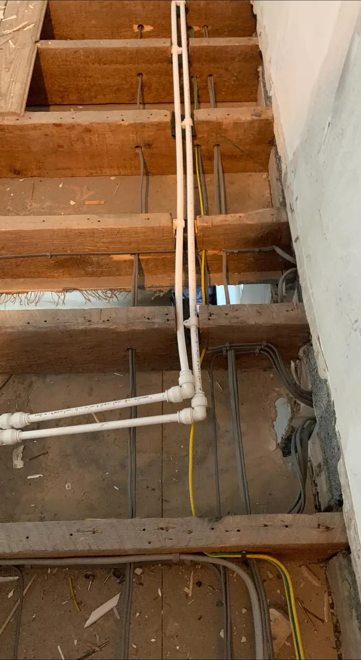 Twin and earth cables run across open floor joists during a rewire