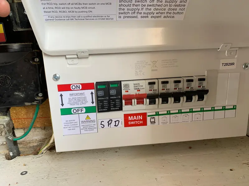 A finished replacement consumer unit with the cover on, main switch and surge protection labelled