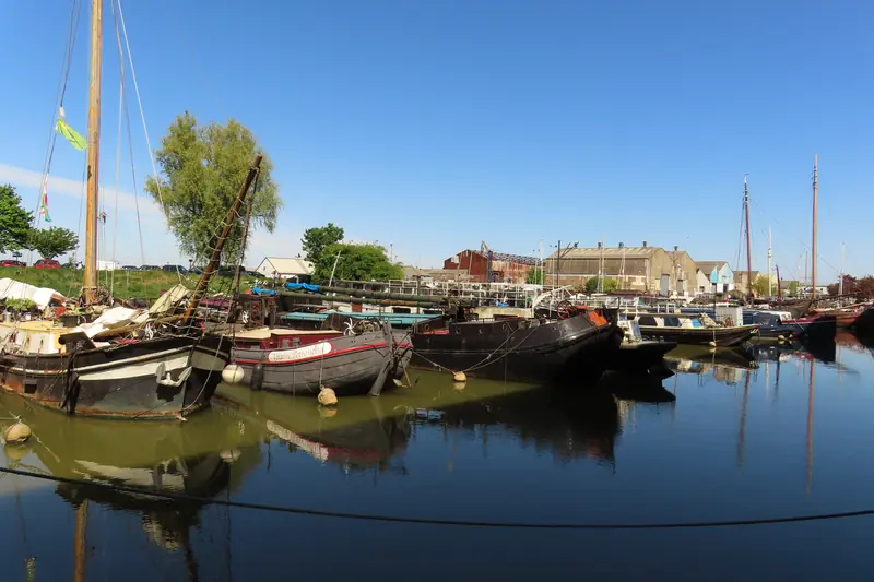 Gravesend Canal Basin: old Thames sailing barges and houseboats moored in still water, masts against a blue sky, warehouses behind