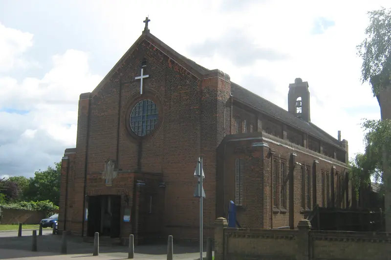 St Martin's, Barnehurst: a red-brick church with a tall gable, a white cross above a round window, and a small bell tower
